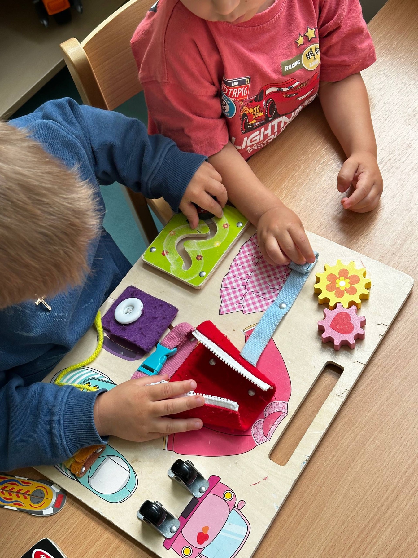 Dzieci wspólnie bawiące się tablicą manipulacyjną